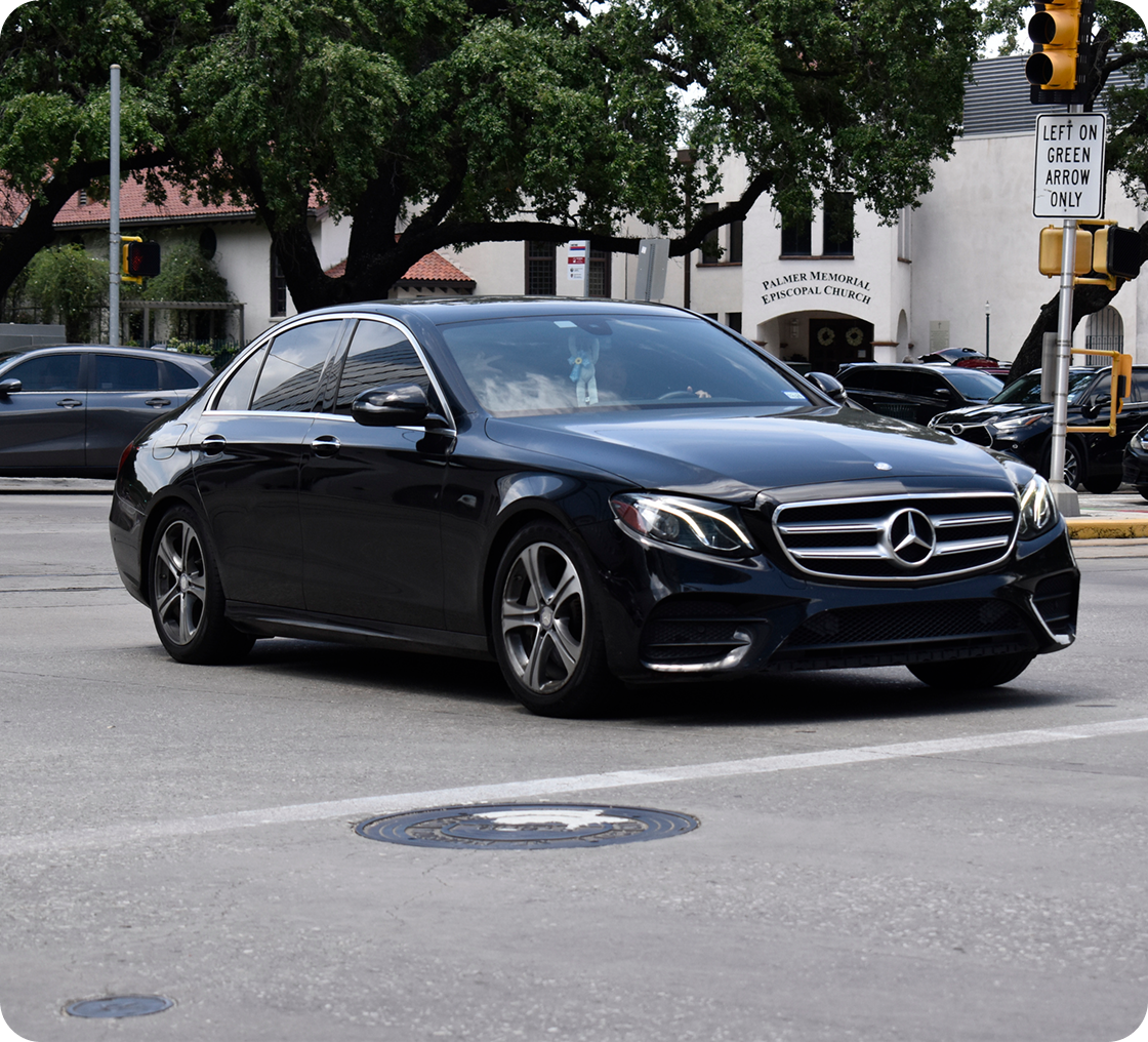 Black Mercedes sedan at city intersection.